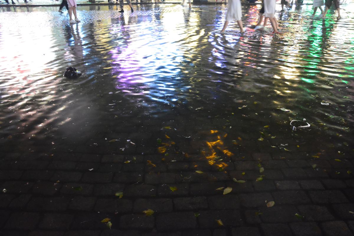 Floodwater covering a street at night, lit by reflected lights