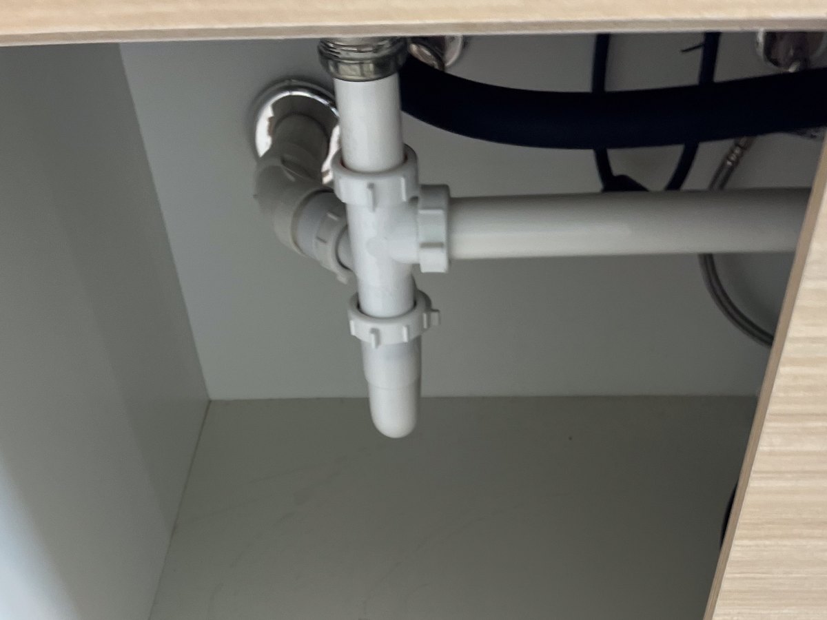 PVC drain piping inside the cabinet under a kitchen sink