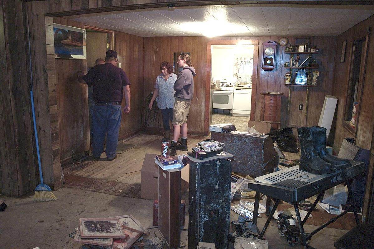 Residents standing in a flood damaged room, the kind of standing water treated with the greatest caution