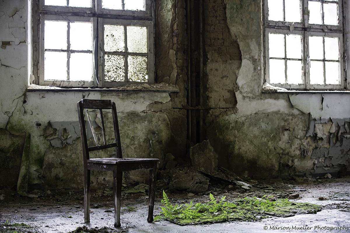 A neglected room with peeling paint, damp damage, and old flood marks on the walls