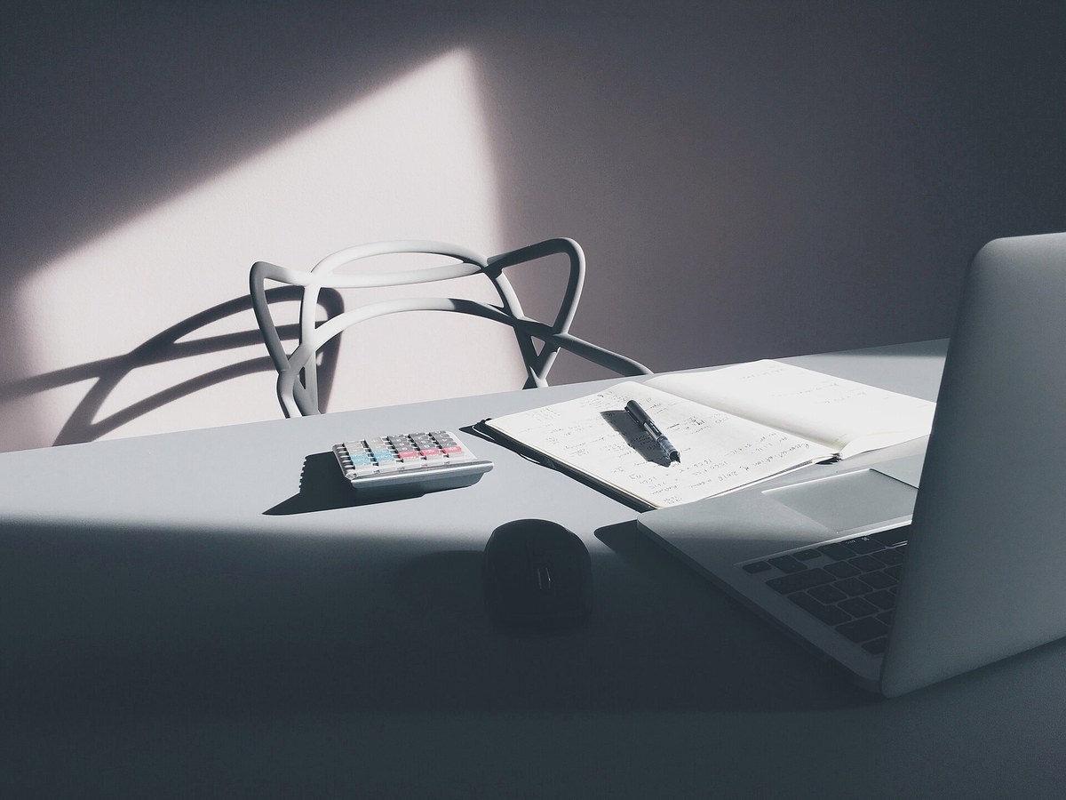 A desk with a laptop, calculator, and notebook used to work through restoration numbers