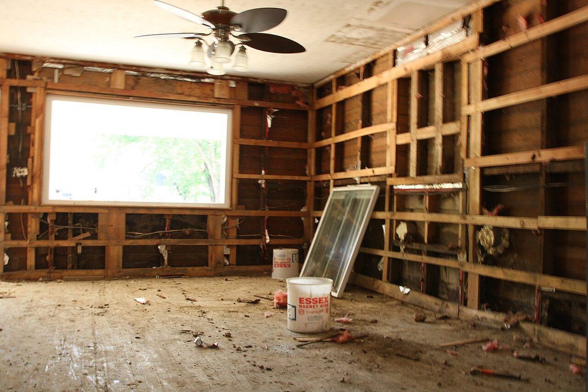 Walls opened to expose framing after the baseboards and lower drywall were removed in a flooded home