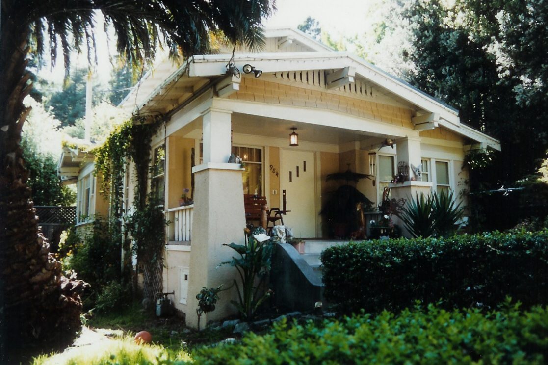 A craftsman style bungalow with a wide front porch and landscaped garden