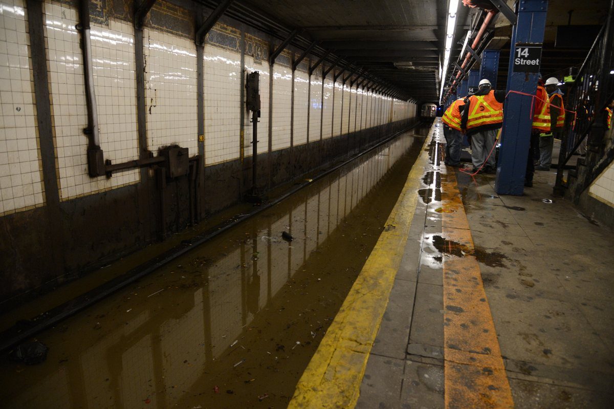 Water from a broken main flooding a transit tunnel as workers look on