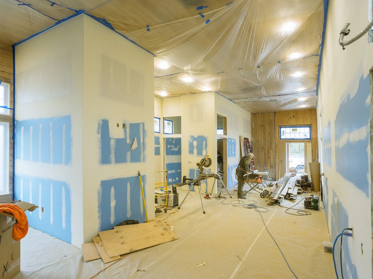 Room mid renovation with new drywall seams taped and plastic sheeting overhead