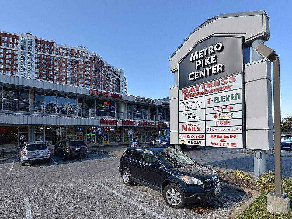 A commercial shopping center sign and storefronts along a Tulsa corridor