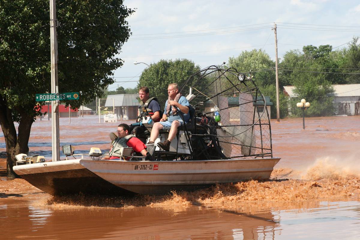 A rescue airboat crossing a flooded residential street during a flood response