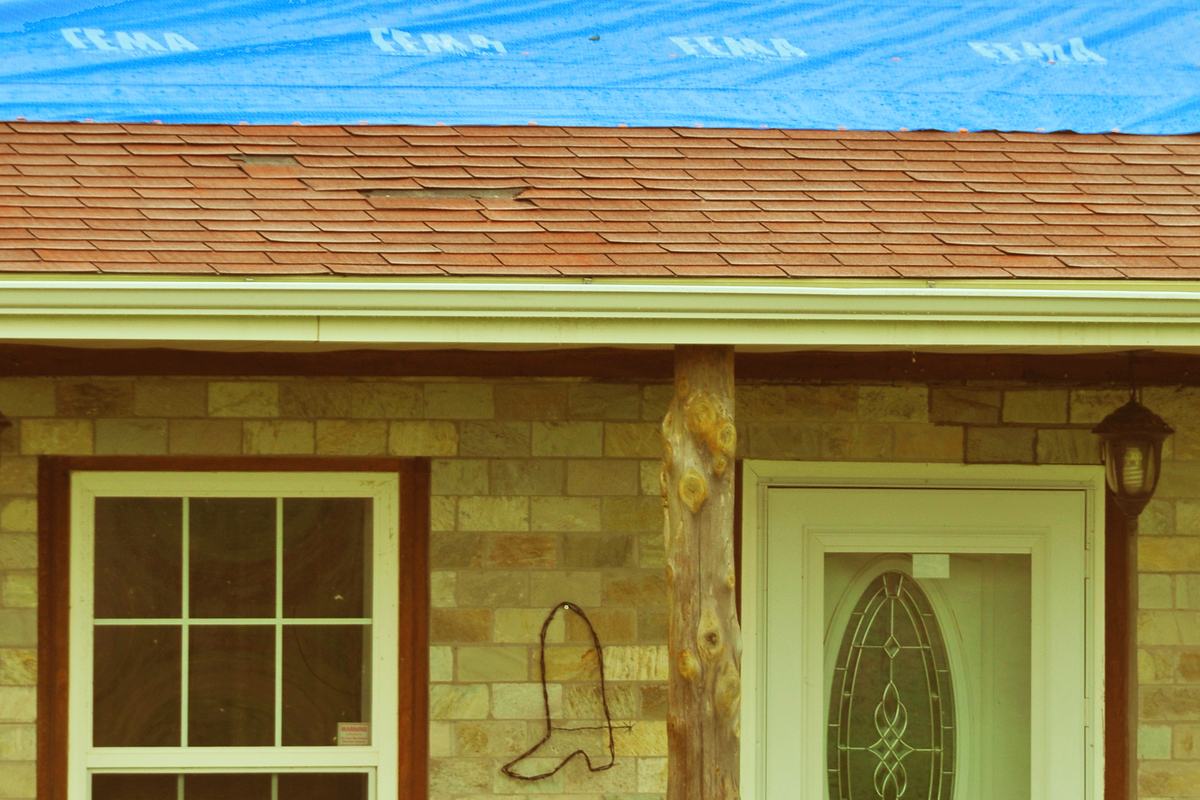 A blue tarp roof cover on a tornado damaged Oklahoma home
