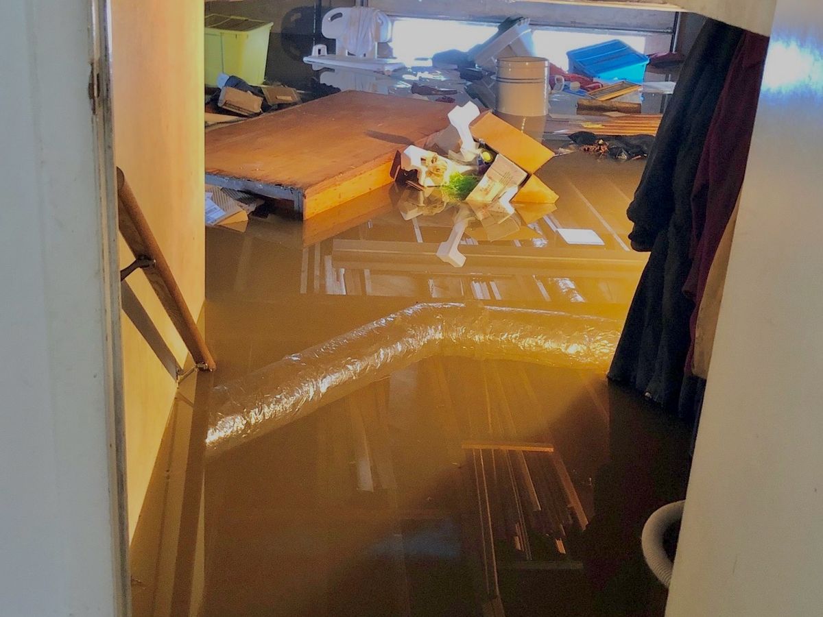 Standing floodwater covering a basement floor with belongings floating in it