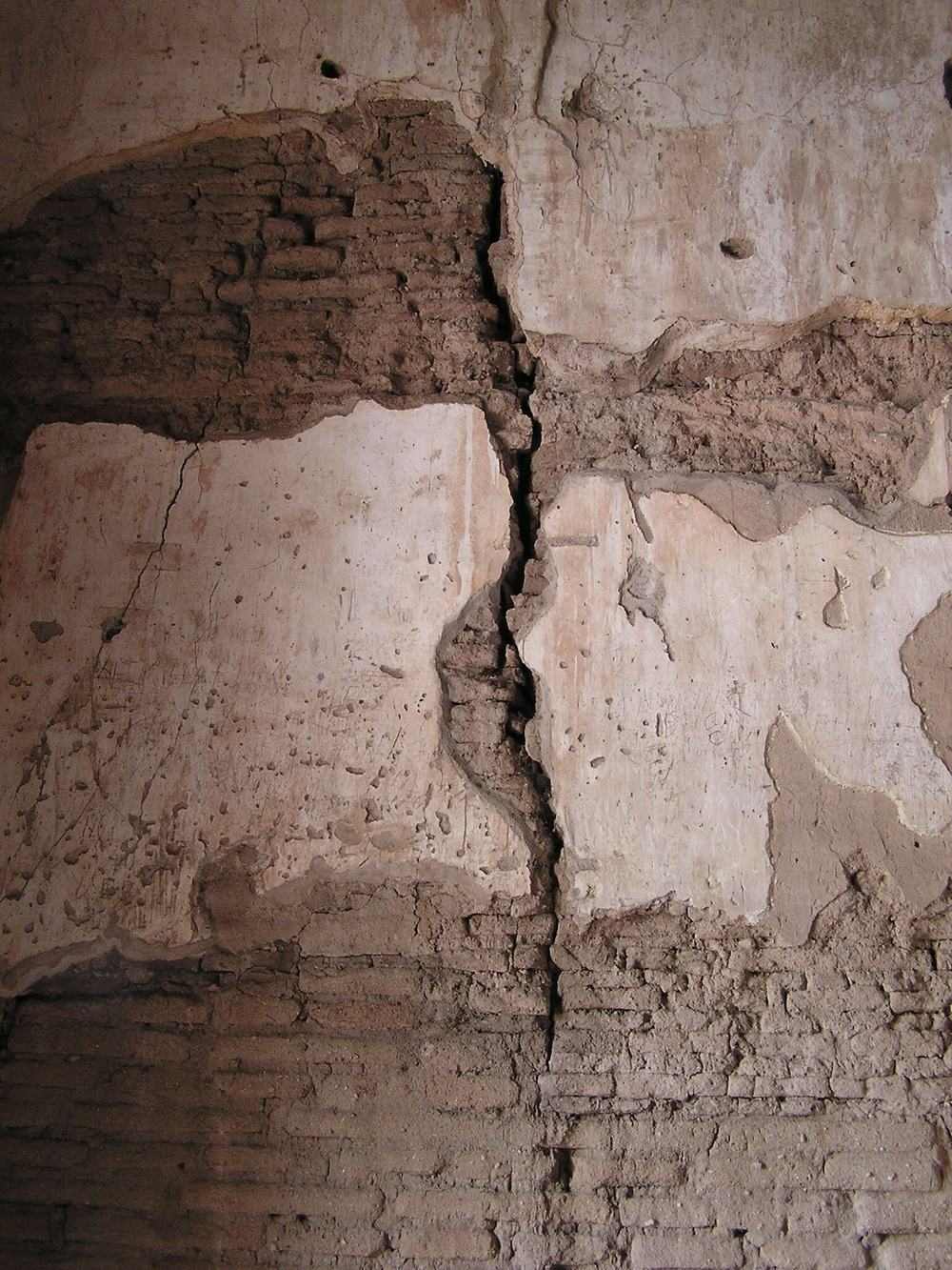 A wide crack running down an old plaster interior wall