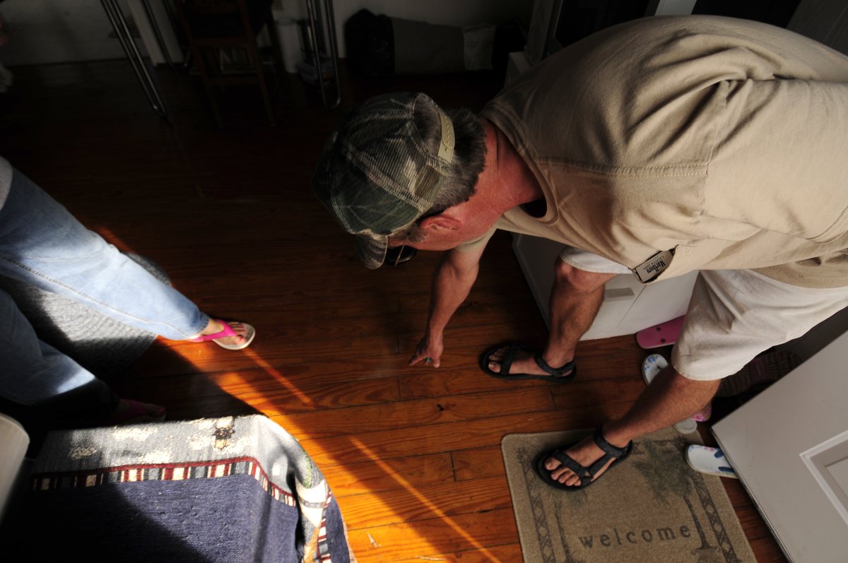 A homeowner inspecting his hardwood floor after flooding