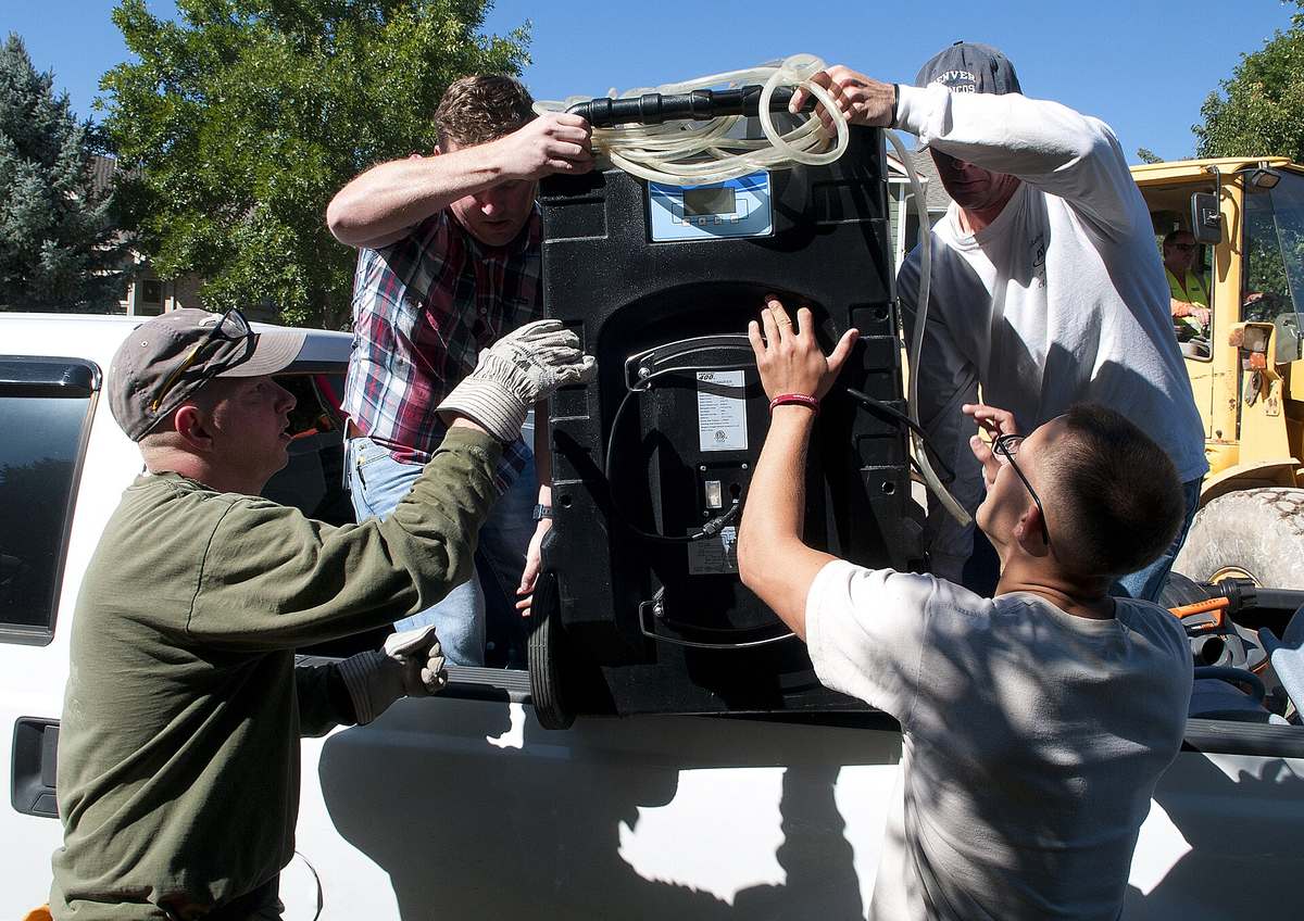 Crew members loading a professional dehumidifier onto a work truck