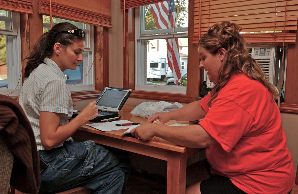 A homeowner reviewing restoration paperwork and documentation at a kitchen table