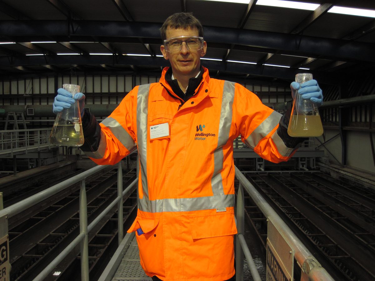 A technician holding water sample flasks for contamination testing