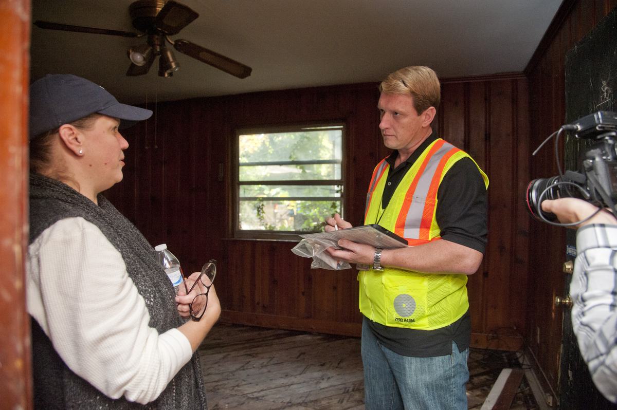 A housing inspector talking through paperwork with a homeowner