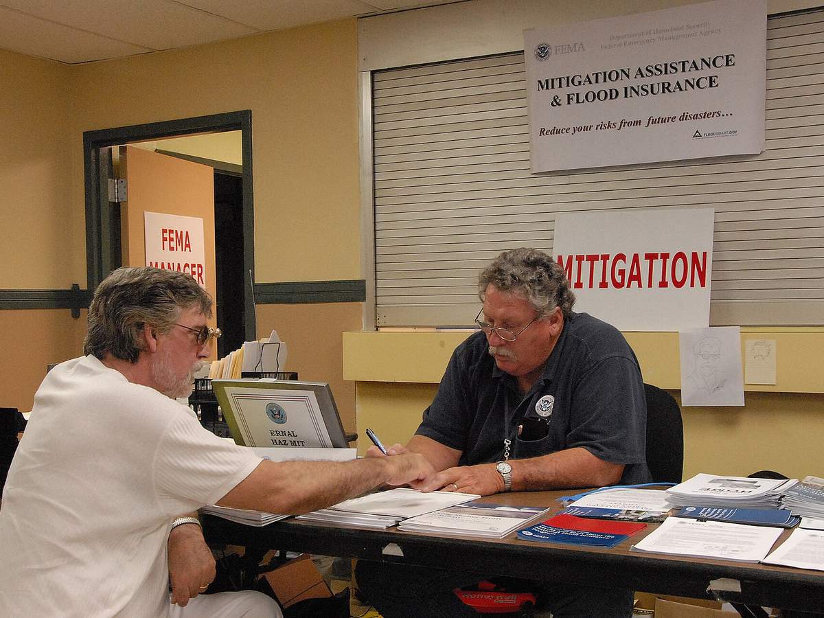 A homeowner reviewing claim paperwork with an assistance worker at a desk