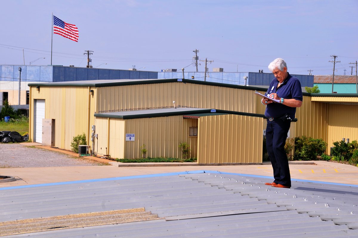 An inspector documenting hail damage on a flat roof in Oklahoma