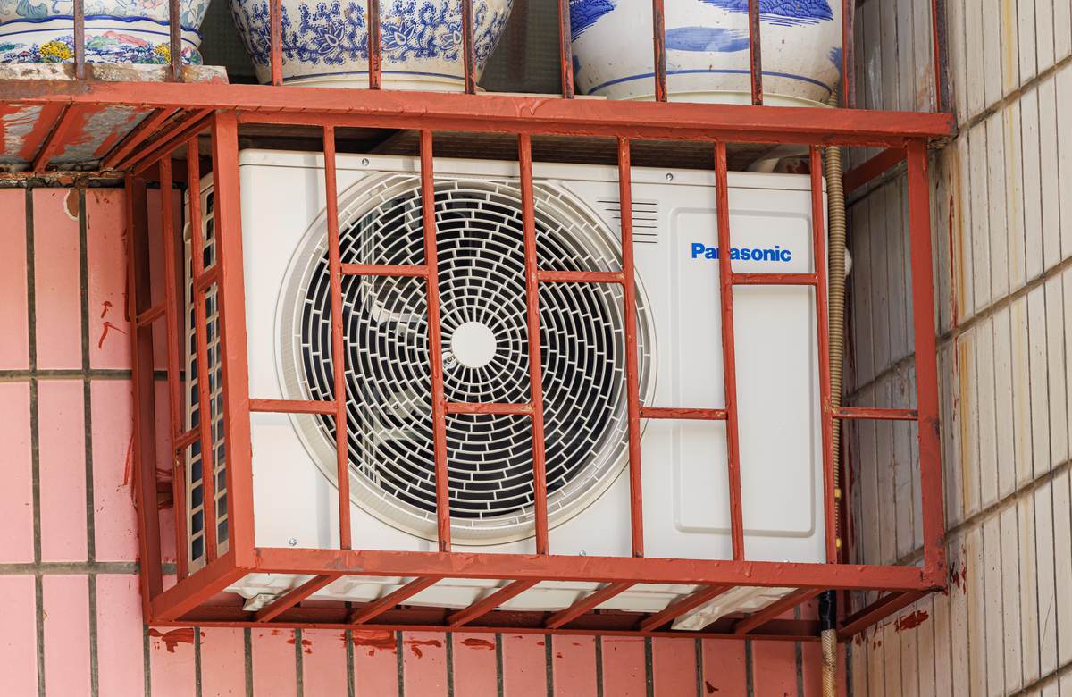 An outdoor air conditioner condenser unit mounted on a building wall