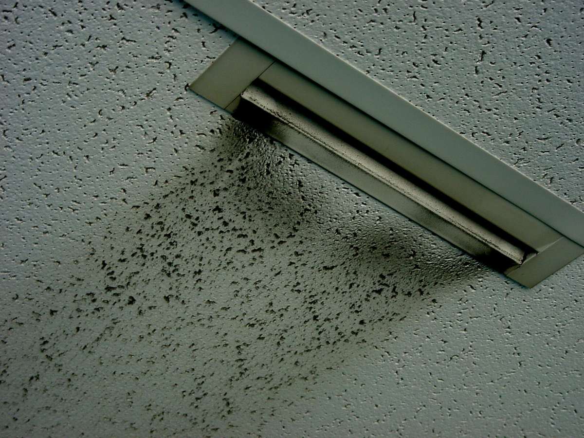 Ceiling air vent with dark particulate staining on the surrounding tiles, showing how airborne particles collect in indoor air