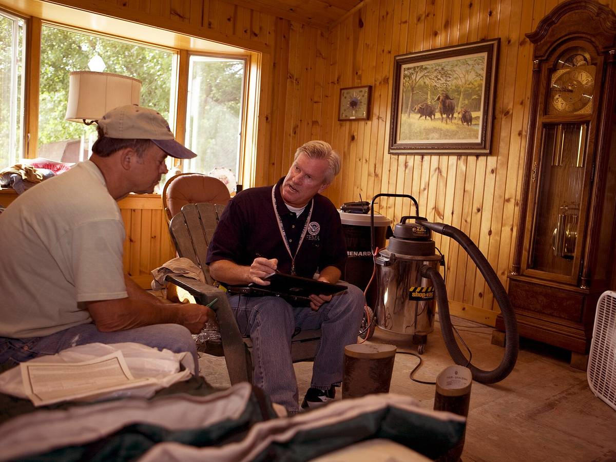 An inspector with a clipboard interviewing a homeowner inside the home during a mold assessment