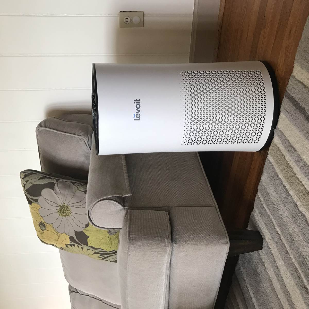 An air purifier running beside a sofa in a living room