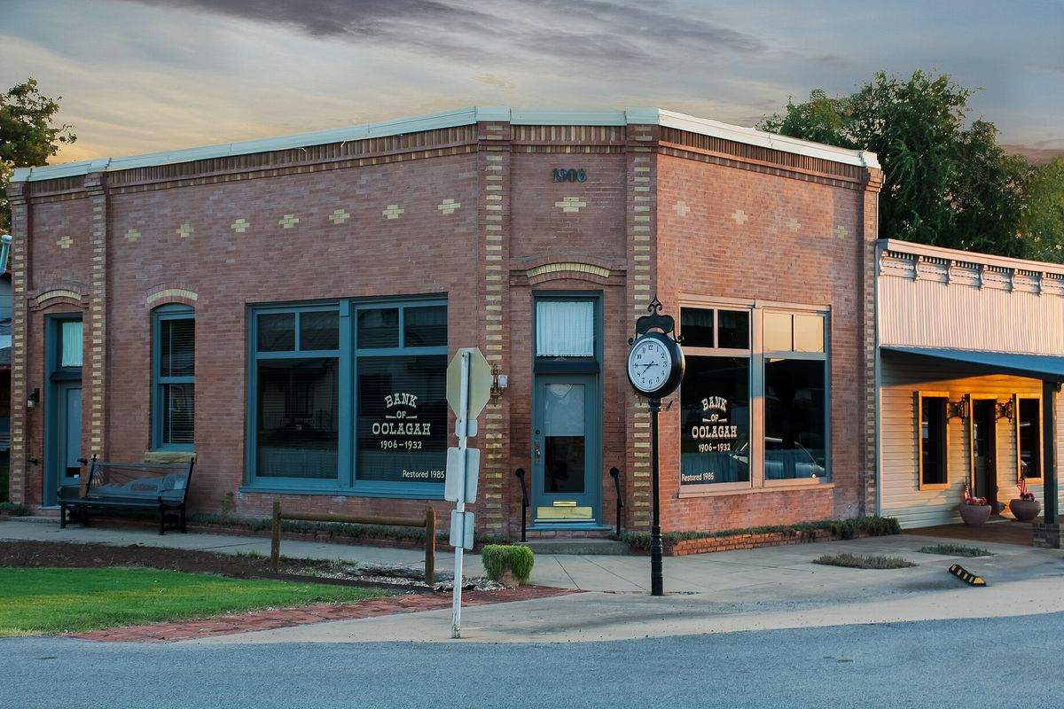 Historic brick bank building with a street clock in downtown Oologah, Oklahoma