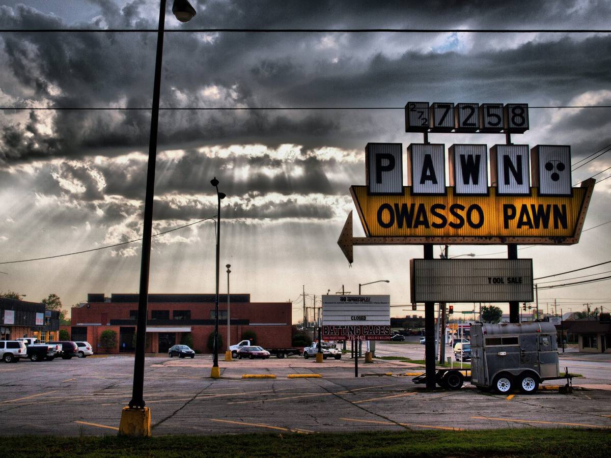The Owasso Pawn sign under a dramatic evening sky in Owasso