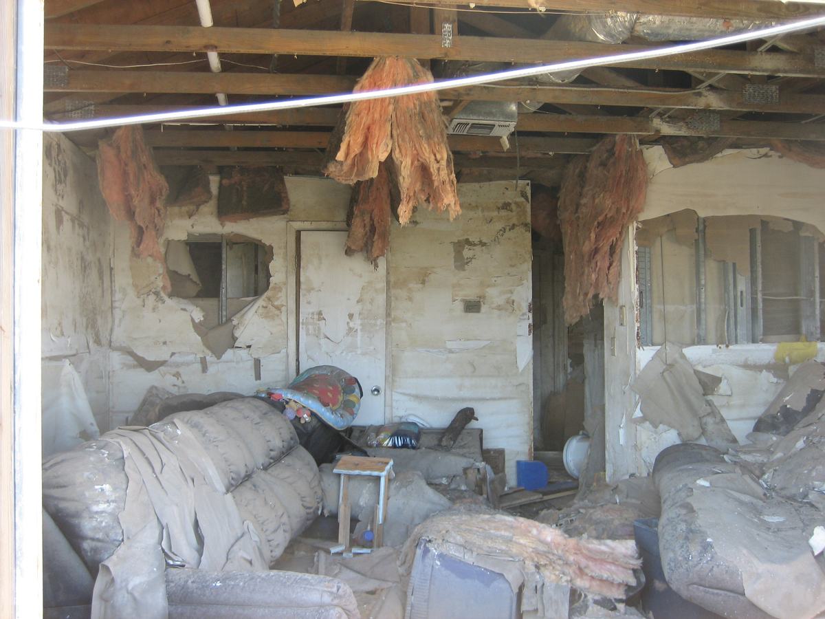 A flood damaged living room with furniture covered and debris on the floor