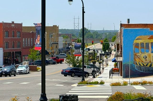 Downtown Sand Springs street with storefronts and a trolley mural