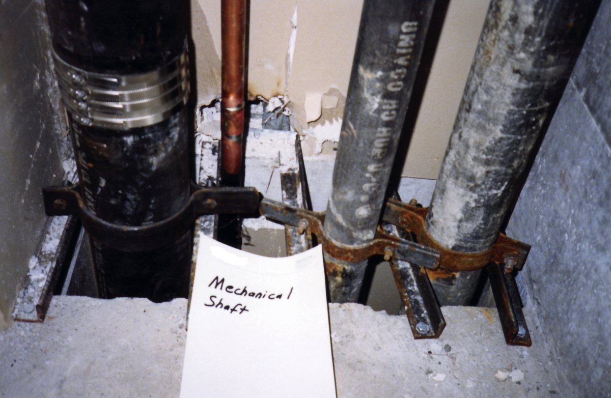 Exposed corroded pipes inside a concrete shaft, the kind of hidden damage slab leaks cause