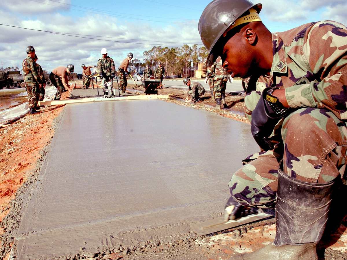 A builder troweling the edge of a freshly poured concrete slab