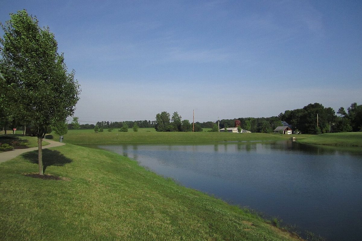 A subdivision retention pond edged with grass, the drainage feature behind many South Tulsa streets