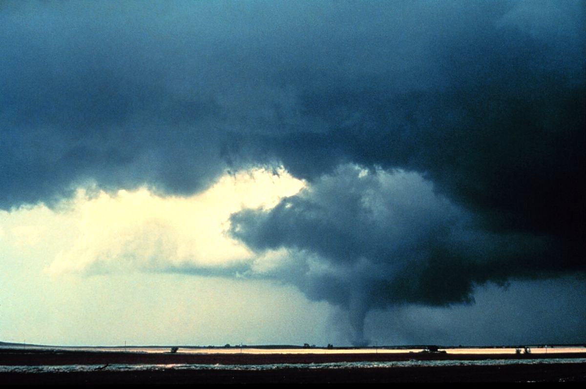 Tornado funnel dropping from a dark supercell storm cloud over open Oklahoma plains