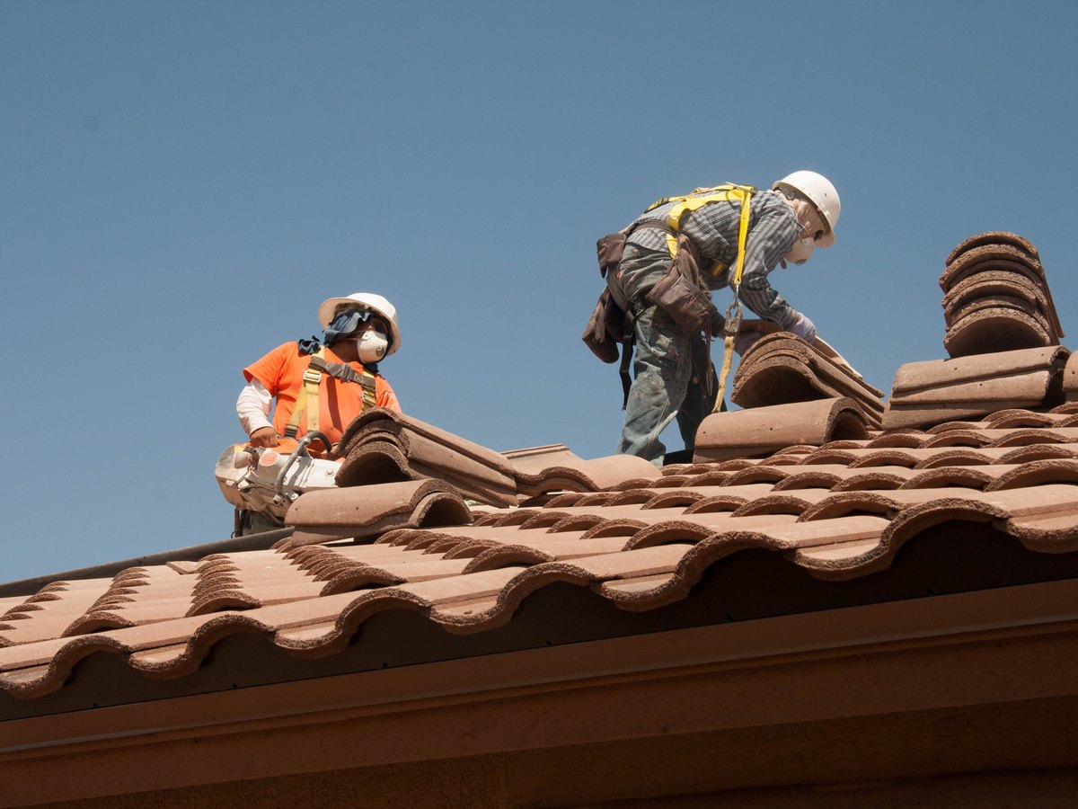 Roofing workers repairing a tile roof after storm damage