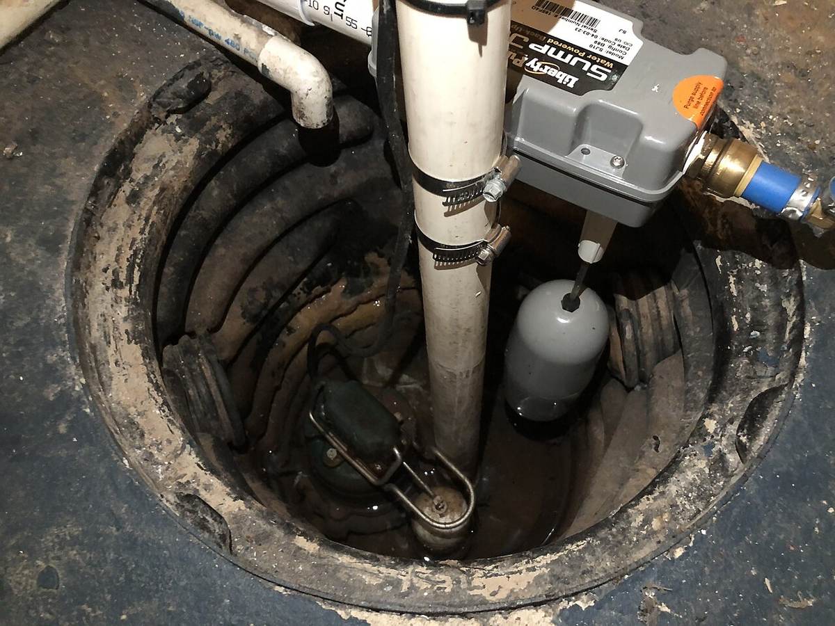 Sump pump, float switch, and discharge pipe inside a basement sump pit, the equipment checked first after a Tulsa sump pump failure flood