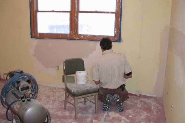 A worker patching and repairing a wall during a home restoration job