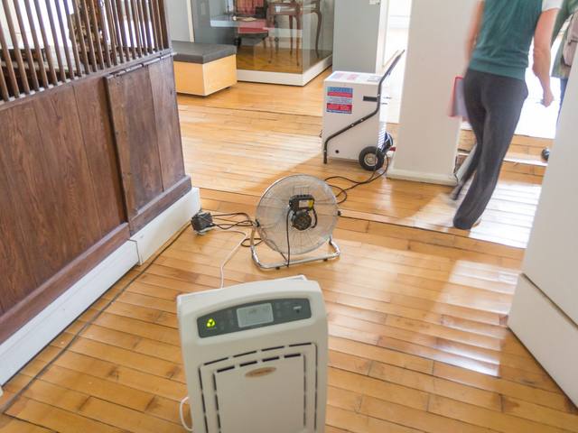 A dehumidifier and an air mover drying a wood floor during a water damage restoration job
