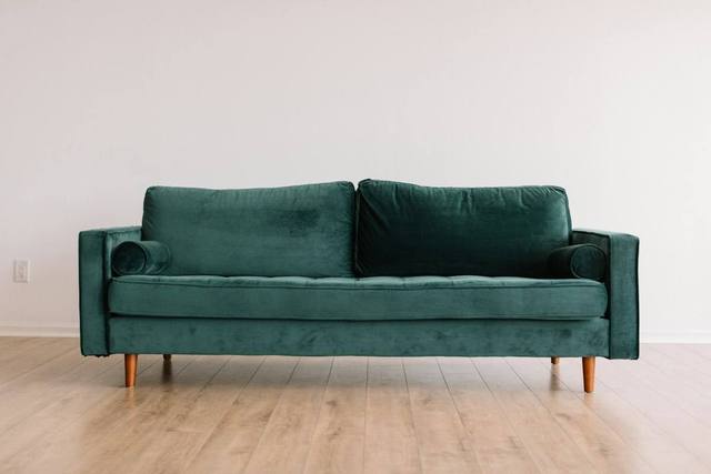 Green upholstered sofa on a light wood floor, the kind of furniture assessed and cleaned during content cleaning after water damage in Tulsa OK