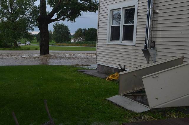 Basement cellar doors open on a Tulsa area home with floodwater standing across the yard after a flash flood