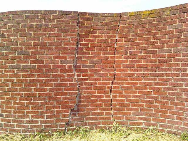 Long vertical cracks running through a brick wall, the kind of foundation movement cracking that lets water into Tulsa basements