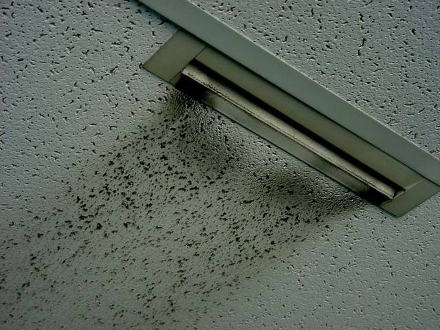 Ceiling air vent with dark particulate staining on the surrounding tiles, showing how airborne particles collect in indoor air