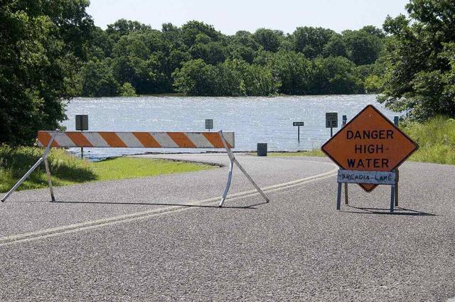 Oklahoma road closed behind a barricade with a Danger High Water sign during flooding