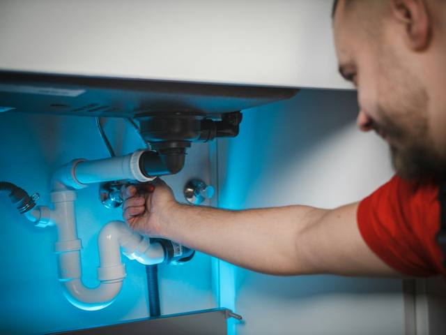 Technician repairing under-sink plumbing, a common water damage source in Tulsa OK homes