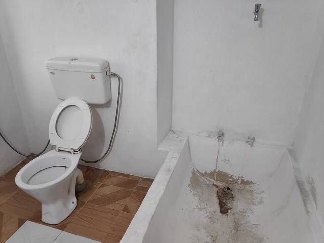 Bathroom toilet and tub in a Tulsa home, where an overflow or failed wax ring can send water across the floor and into the ceiling below