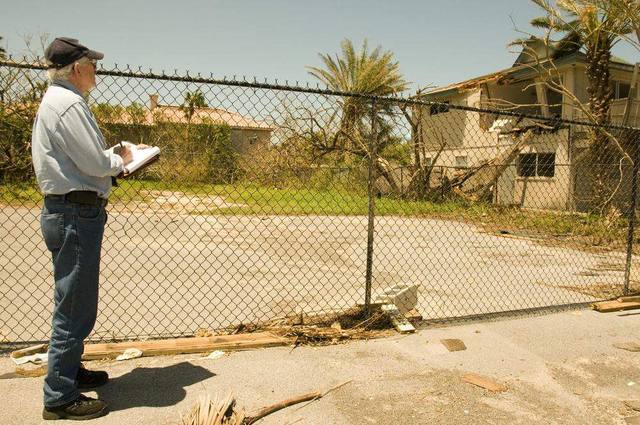 A damage inspector with a clipboard documenting a storm damaged home
