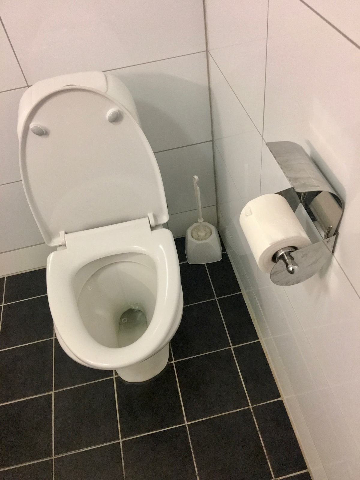 A toilet in a small tiled bathroom