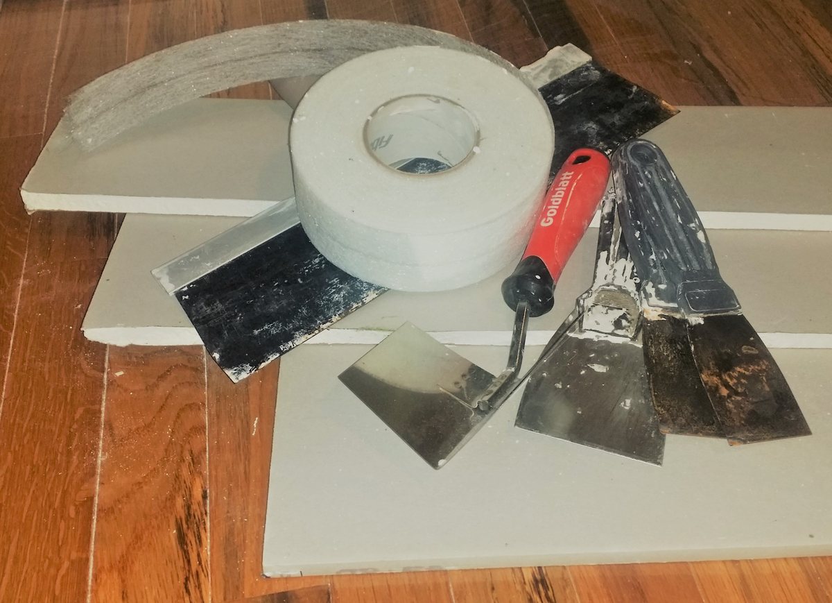 Drywall sheets, joint tape and taping knives ready for repairs