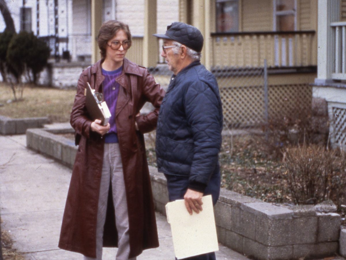 Two inspectors with a clipboard talking with a homeowner outside the house during an assessment