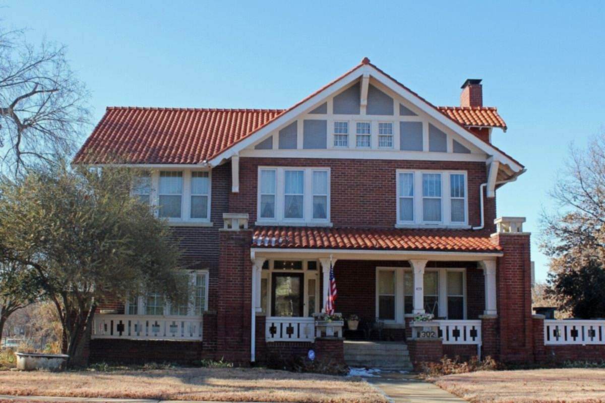 Brick craftsman home with a tiled roof and front porch in Oklahoma, representative of Turley established homes