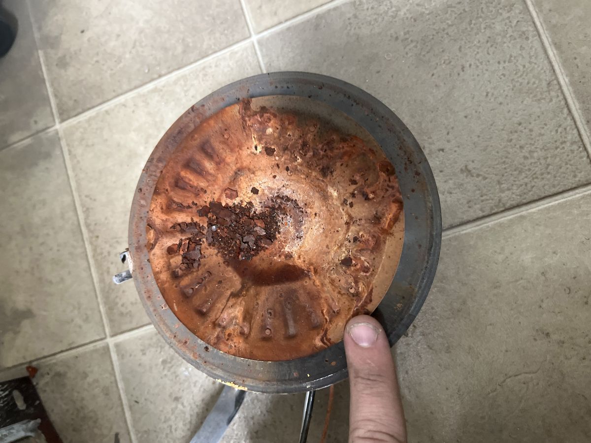 Corroded water heater burner plate removed from a rusted tank